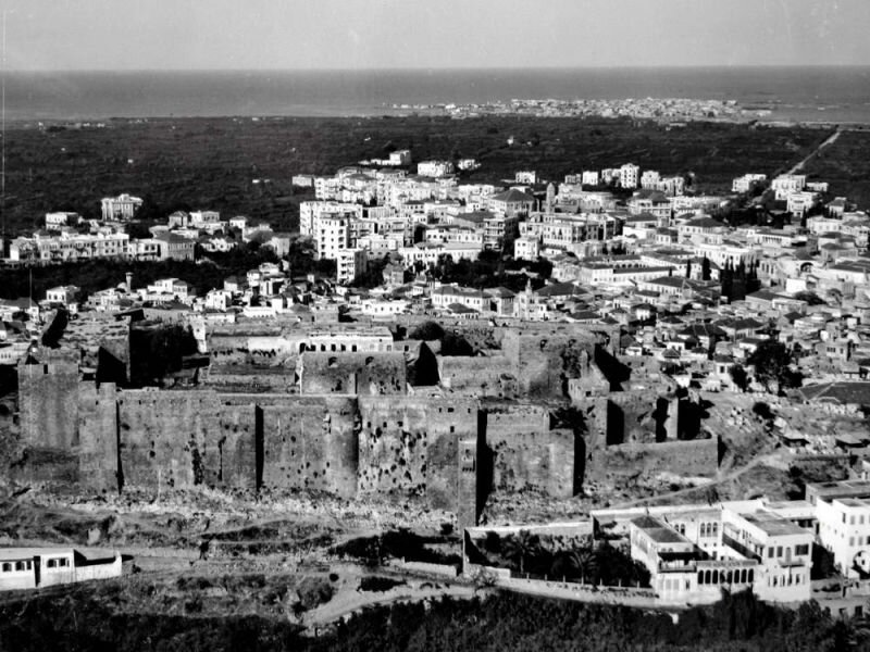 Aerial view of the Tripoli Citadel with a view of Tripoli (center, center right), Abou Ali River (top right), and AlMina in the distance (November 20, 1933).